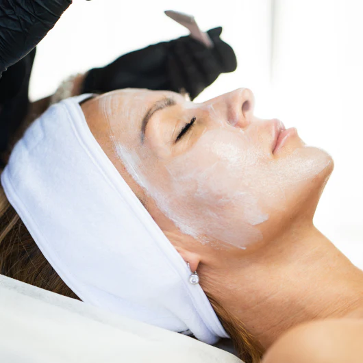 Person receiving a facial treatment with a face mask applied
